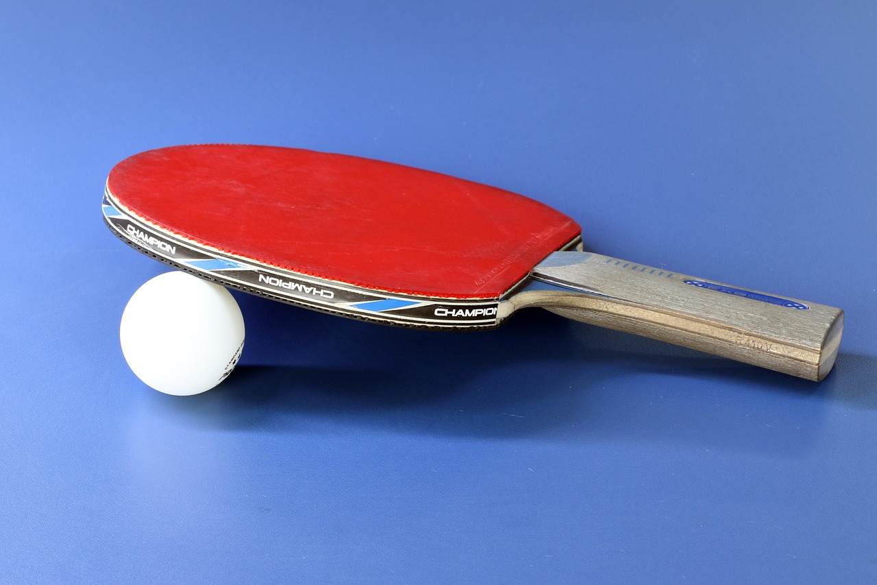 Tischtennis-Schläger und Tischtennisball auf einem blauen Tisch