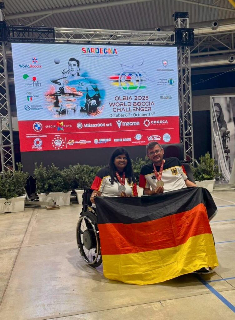 Anita Raguwaran und Boris Nicolai halten gemeinsam eine Deutschland-Flagge. Im Hintergrund ist ein Banner zu sehen.